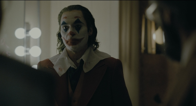 Medium shot frame from Joker — standing, room, mirror