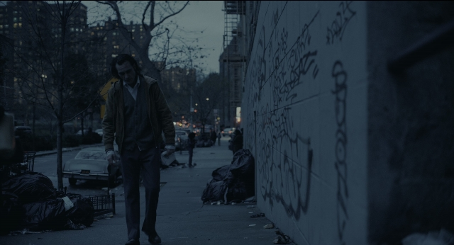 Wide shot frame from Joker — walking, street, car