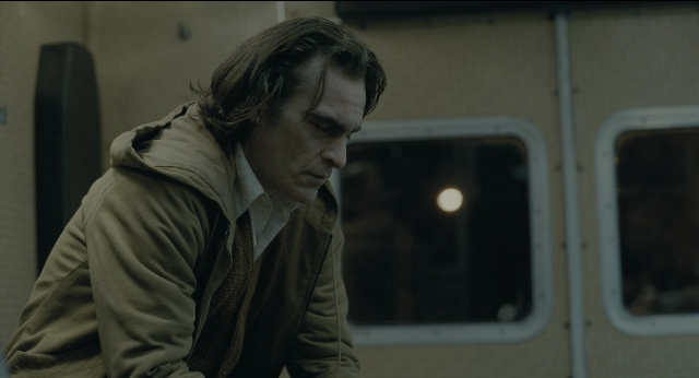 Wide shot frame from Joker — standing, car, face