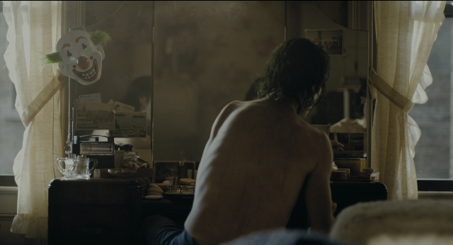 Wide shot frame from Joker — sitting, room, mirror
