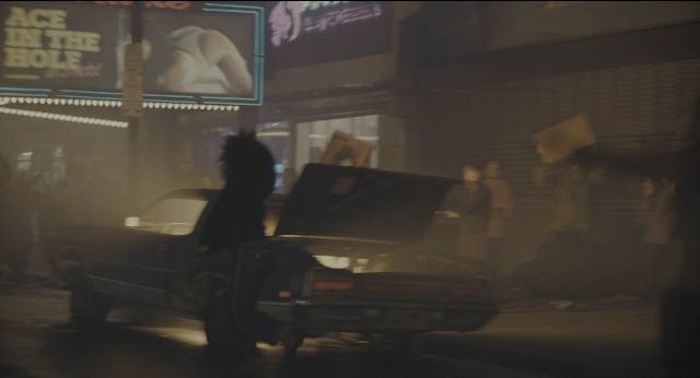 Wide shot frame from Joker — walking, street, car
