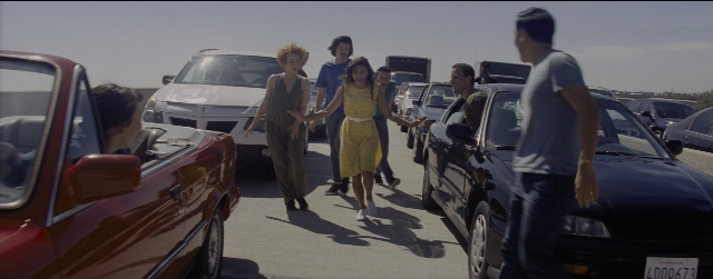 Wide shot frame from La La Land — walking, car, dress