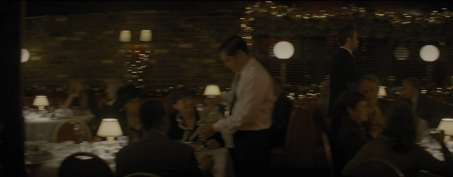 Wide shot frame from La La Land — sitting, standing, table