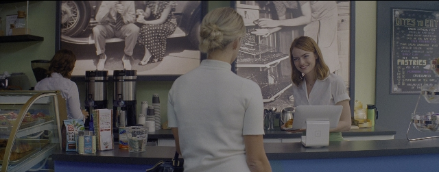 Wide shot frame from La La Land — sitting, standing, table