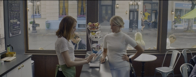 Wide shot frame from La La Land — sitting, standing, table
