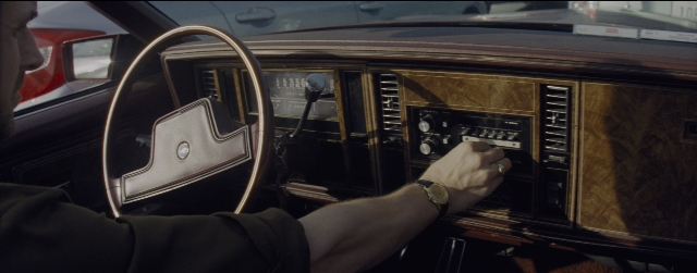 Wide shot frame from La La Land — street, car, hand