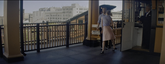 Wide shot frame from La La Land — standing, door, hat