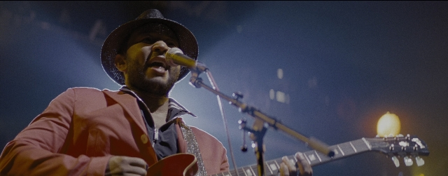 Wide shot frame from La La Land — hat, microphone, guitar