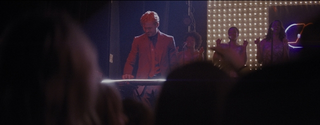 Wide shot frame from La La Land — standing, dialogue, suit