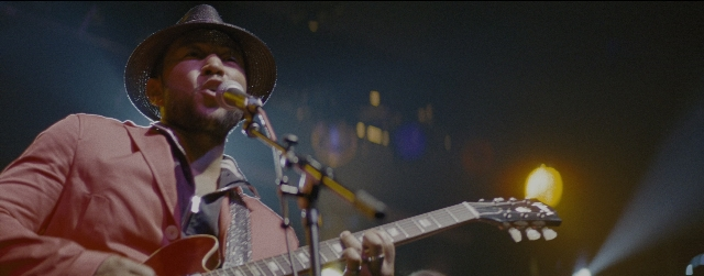 Wide shot frame from La La Land — hat, suit, microphone