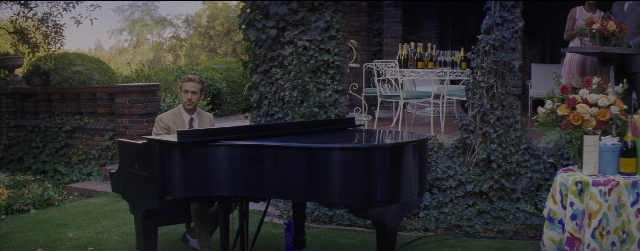 Wide shot frame from La La Land — sitting, standing, table