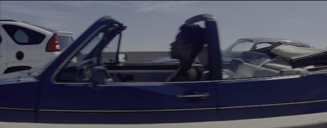 Wide shot frame from La La Land — sitting, door, car
