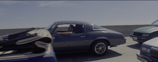 Wide shot frame from La La Land — sitting, door, car