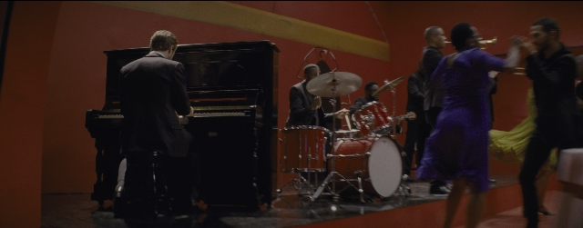 Wide shot frame from La La Land — standing, room, table