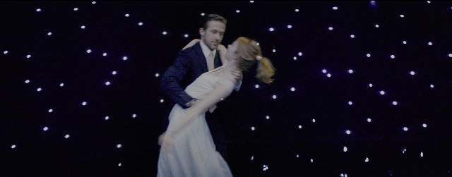 Wide shot frame from La La Land — standing, kiss, suit