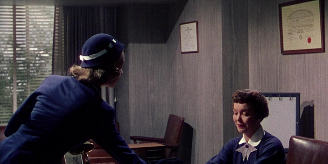 Wide shot frame from Magnificent Obsession — sitting, room, hat