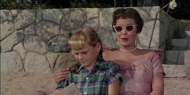 Wide shot frame from Magnificent Obsession — sitting, book, hand