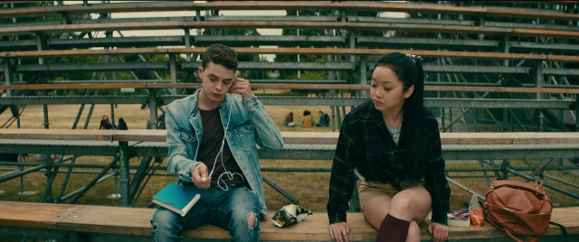 Wide shot frame from To All the Boys I've Loved Before — sitting, book, hand