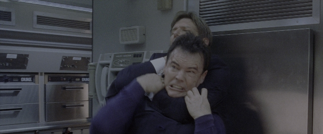 Wide shot frame from Air Force One — room, suit, face