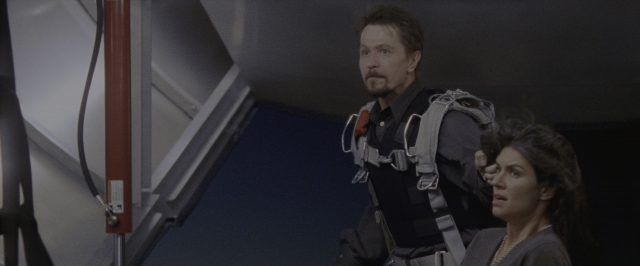 Wide shot frame from Air Force One — standing, room, suit