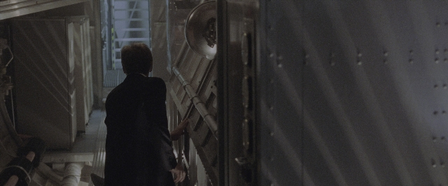 Wide shot frame from Air Force One — standing, door, suit