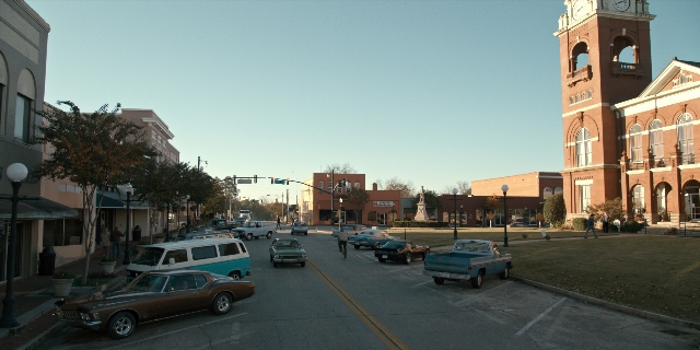 Wide shot frame from Stranger Things — street, car, tower