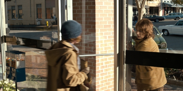 Wide shot frame from Stranger Things — standing, door, street