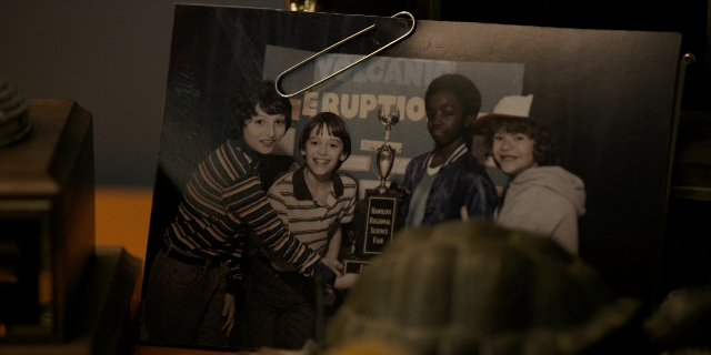 Wide shot frame from Stranger Things — standing, room, table