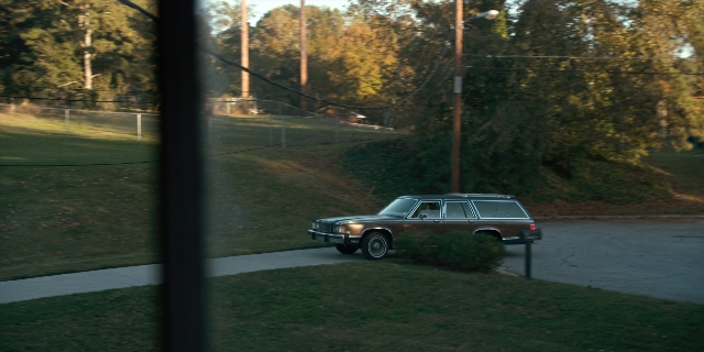 Wide shot frame from Stranger Things — street, car, wheel