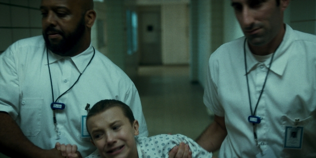 Wide shot frame from Stranger Things — standing, door, hand