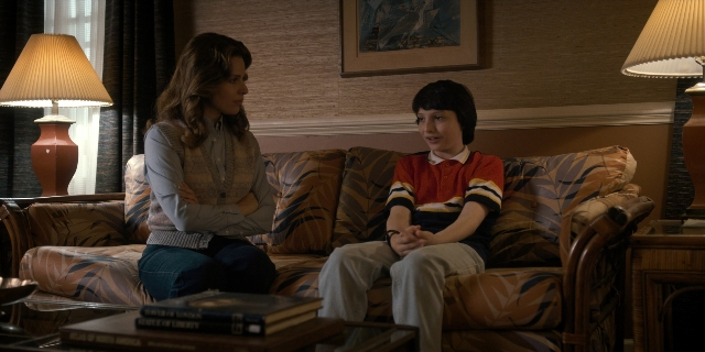 Wide shot frame from Stranger Things — sitting, room, table