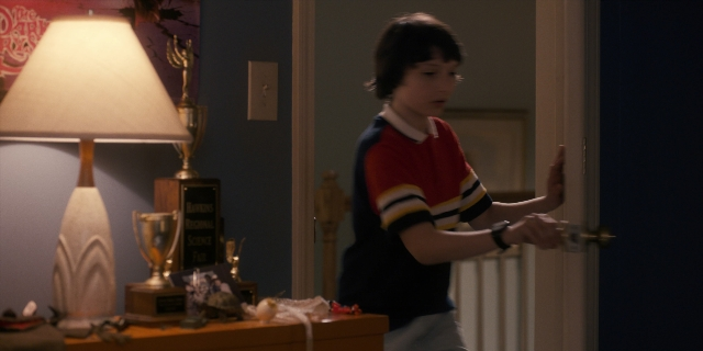 Wide shot frame from Stranger Things — standing, room, table