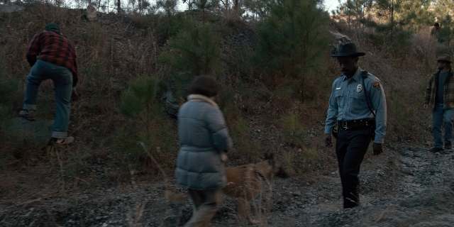 Wide shot frame from Stranger Things — walking, hat, uniform