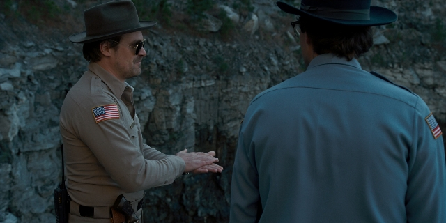 Wide shot frame from Stranger Things — standing, dialogue, hat