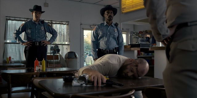 Wide shot frame from Stranger Things — standing, room, table