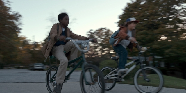 Wide shot frame from Stranger Things — dialogue, street, hat
