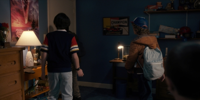 Wide shot frame from Stranger Things — standing, room, hat