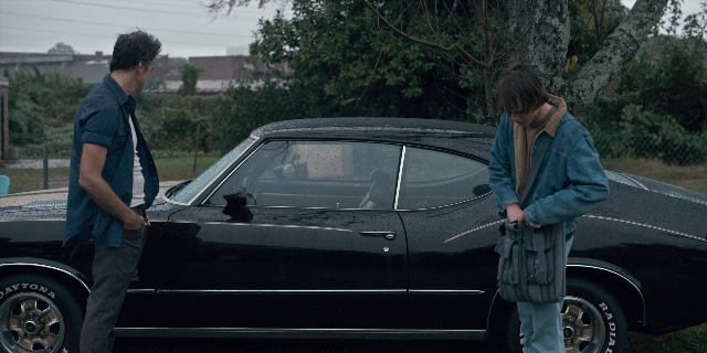Wide shot frame from Stranger Things — standing, car, wheel