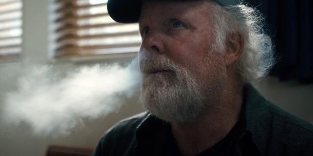 Medium shot frame from Stranger Things — sitting, room, hat
