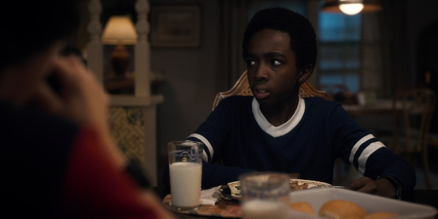 Wide shot frame from Stranger Things — sitting, plate, room