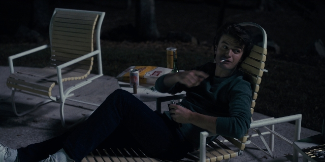 Wide shot frame from Stranger Things — sitting, table, hand