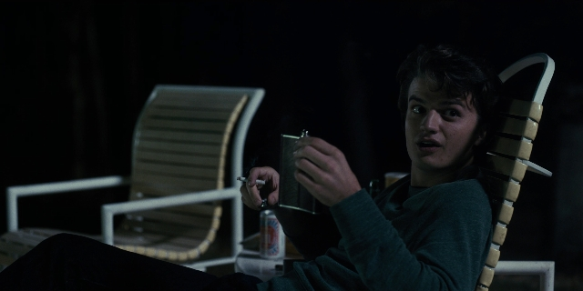 Wide shot frame from Stranger Things — sitting, room, table