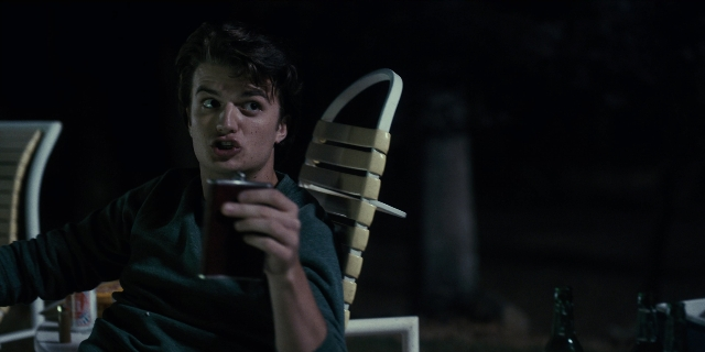 Wide shot frame from Stranger Things — sitting, room, table