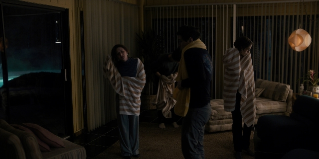 Wide shot frame from Stranger Things — standing, room, table