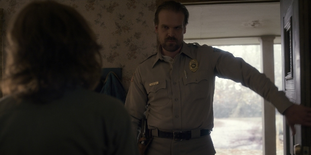 Wide shot frame from Stranger Things — standing, door, uniform