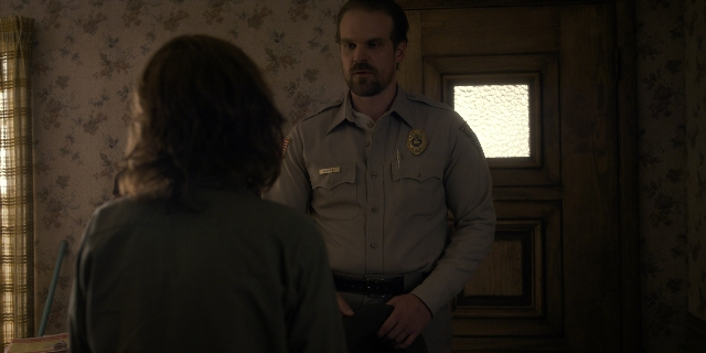 Wide shot frame from Stranger Things — standing, room, door