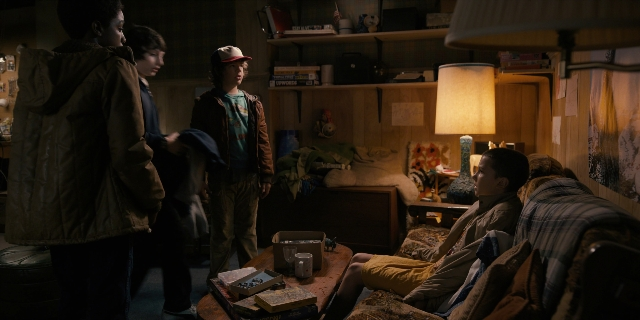Wide shot frame from Stranger Things — sitting, standing, room