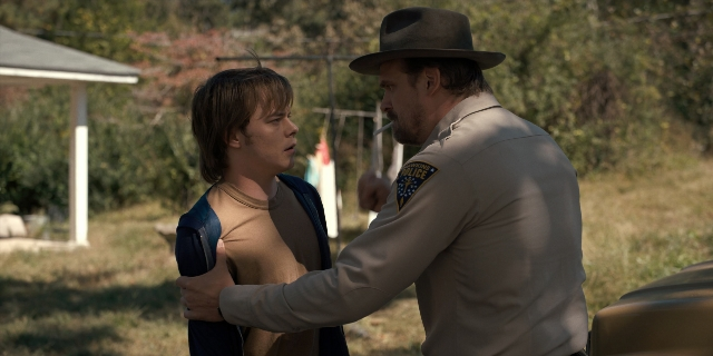 Wide shot frame from Stranger Things — standing, dialogue, hat