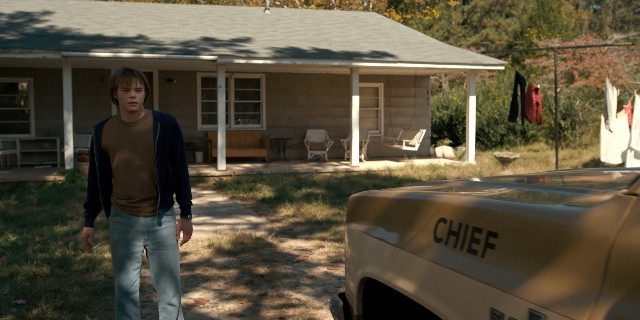 Wide shot frame from Stranger Things — standing, car, house