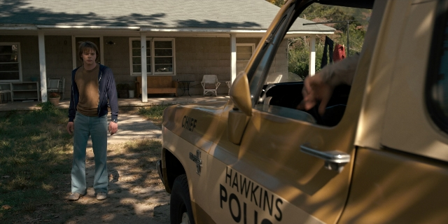 Wide shot frame from Stranger Things — standing, street, house